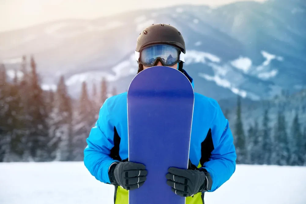 Kayak merkezinde snowboard taşıyan kış sporcusu